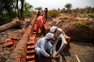 Workers building a concrete water channel in Rakh Bangali village, Punjab province.